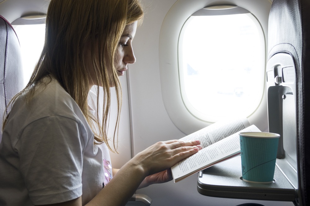 woman reading a book in a plane